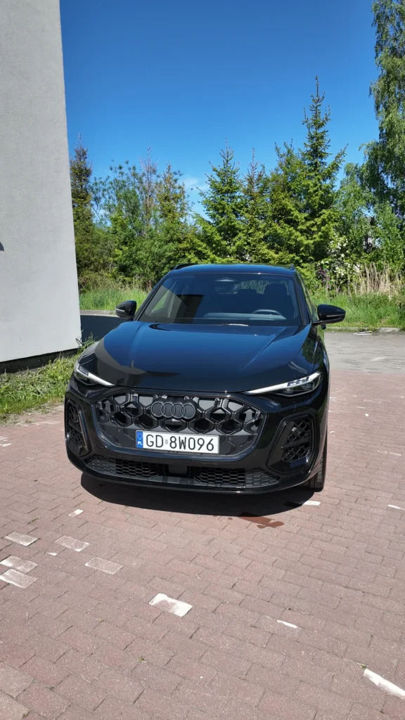 Czarny SUV marki Audi zaparkowany na utwardzonym parkingu.