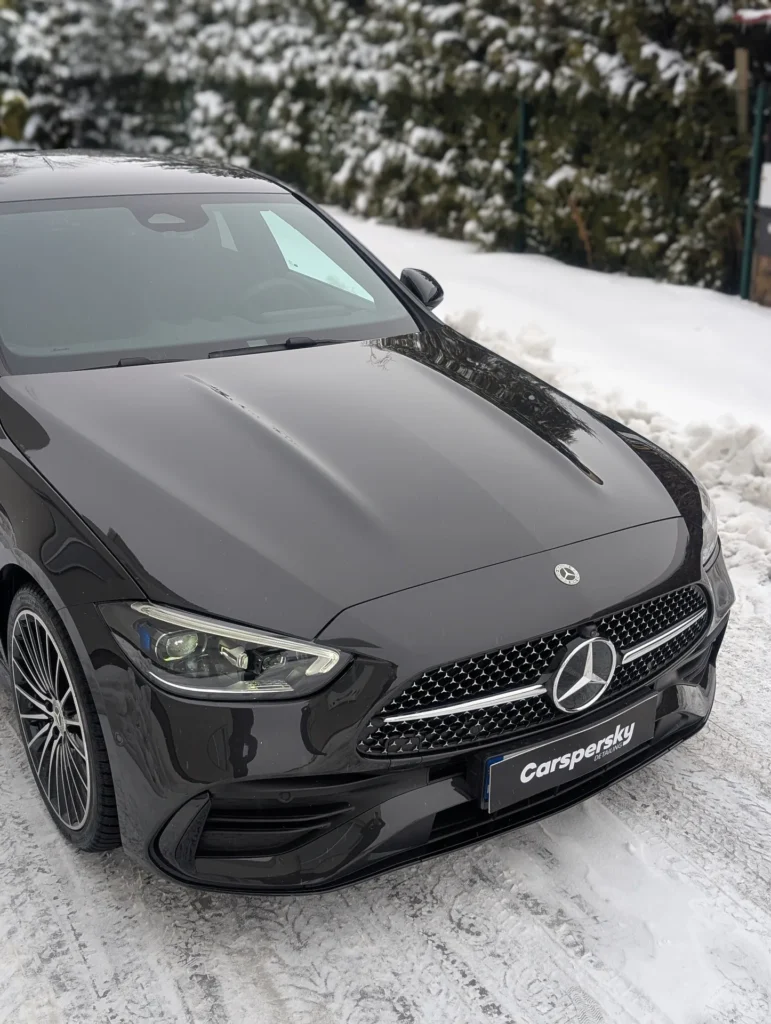 Czarny sedan marki Mercedes-Benz o satynowym wykończeniu zaparkowany na zaśnieżonej nawierzchni.