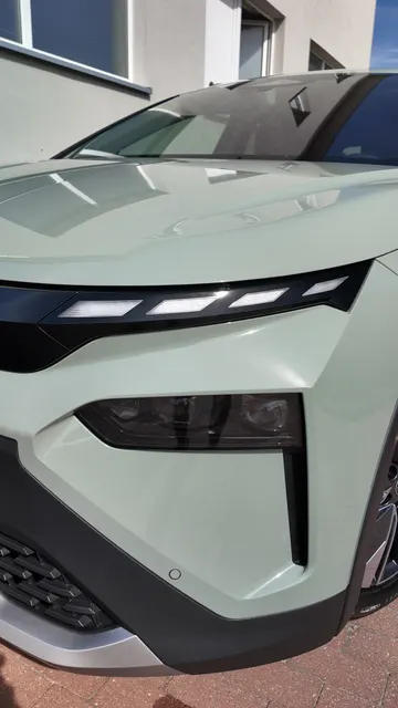 Zbliżenie na przedni róg SUV-a w kolorze szałwiowej zieleni, pokrytego folią ochronną FULL FRONT PPF, ukazujące kanciaste reflektory LED i czarną listwę zderzaka.