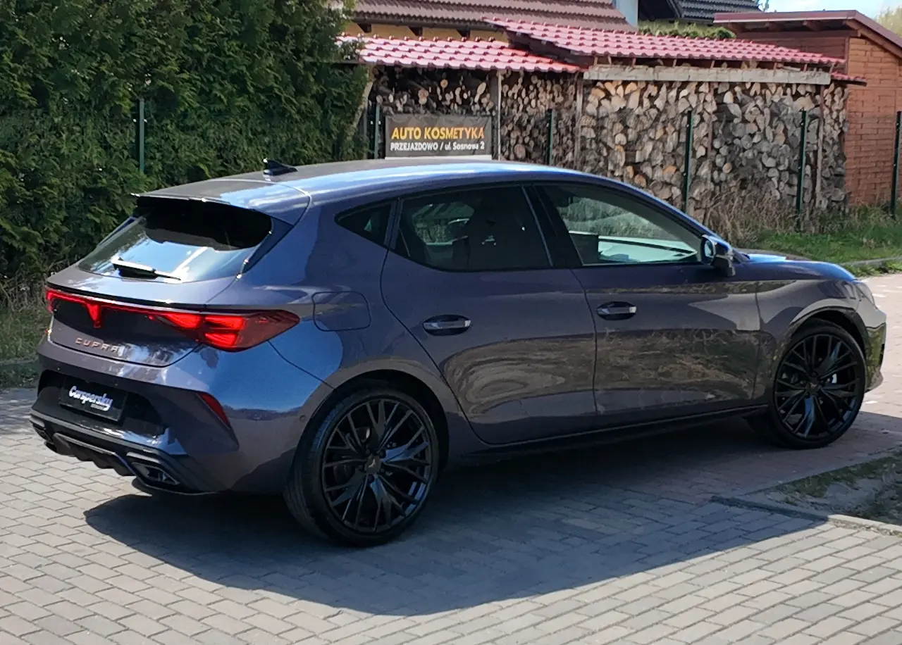 Szary hatchback marki Cupra, zabezpieczony folią PPF, zaparkowany na utwardzonym podjeździe.
